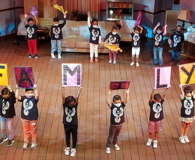 Students holding letters that spell FAMILY on stage