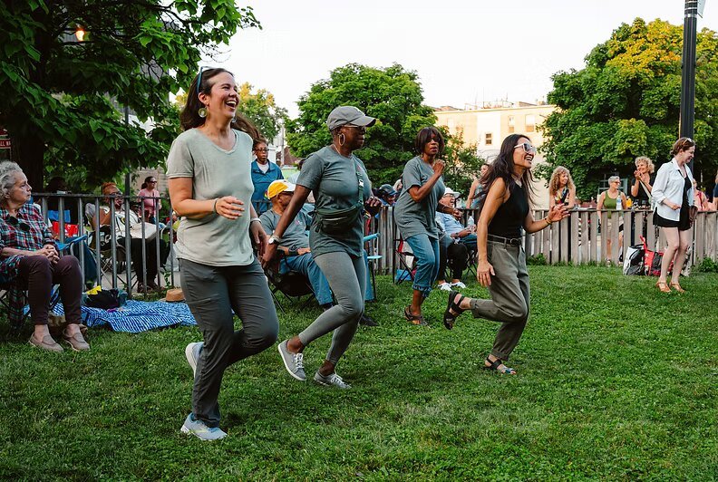 Neighbors dancing outdoors at Fridays on the Green in Uptown