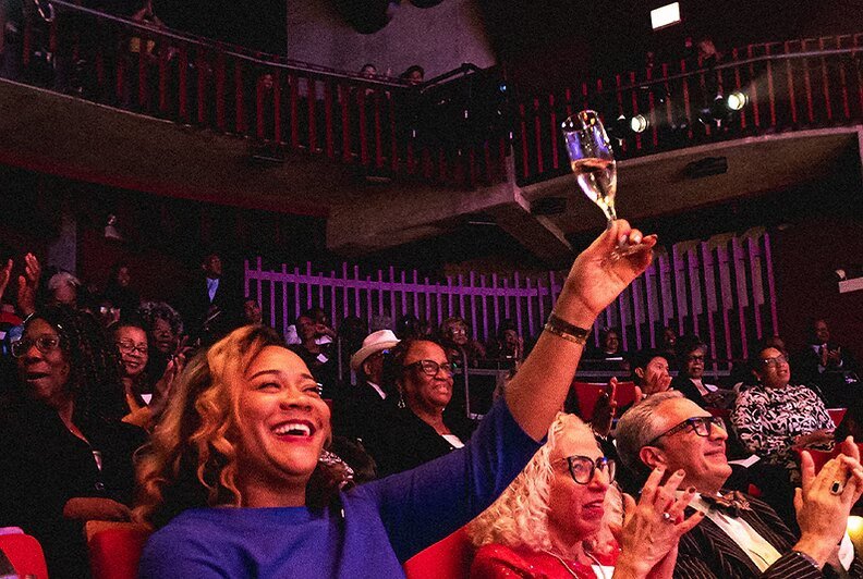 A celebrating audience raising a toast at Black Ensemble Theater