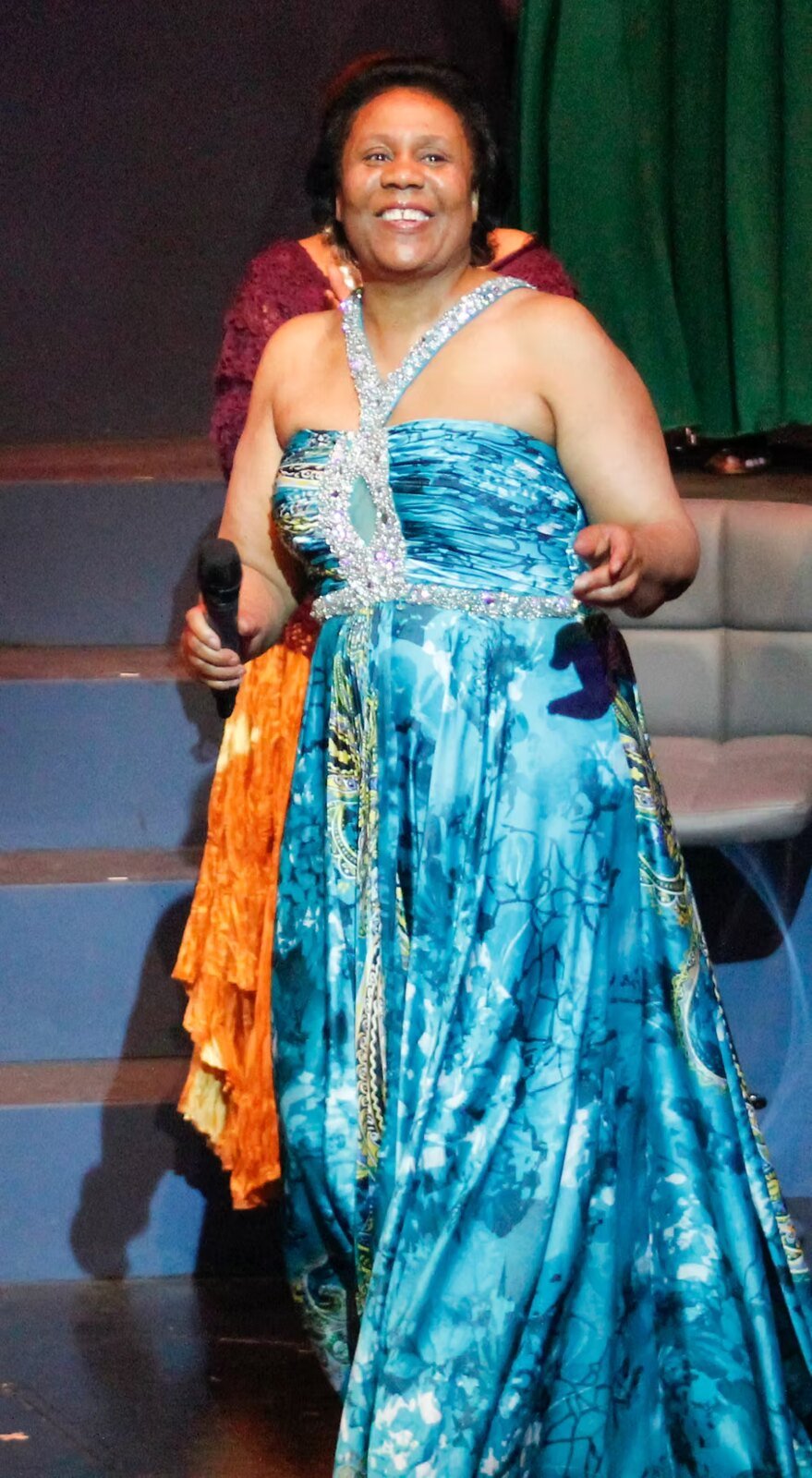 A singer in a flowing blue gown performing